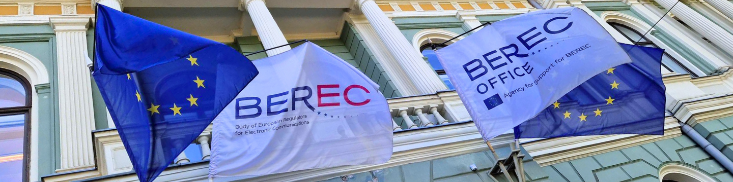 The image shows two flags of the European Union, one flag with the BEREC logo and one flag with the BEREC Office, located above the entrance of the BEREC Office premises in Riga, Latvia