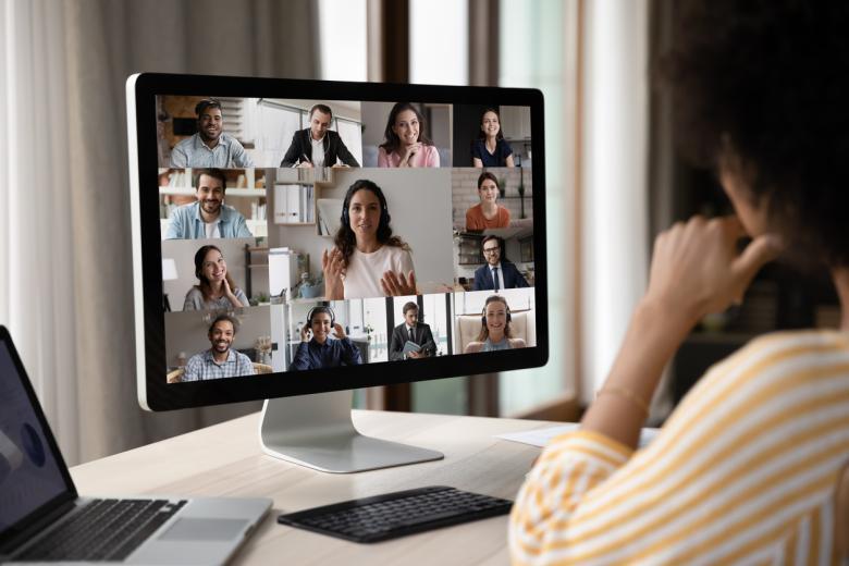 The image shows a woman sitting in front of the PC, participating in an online meeting.