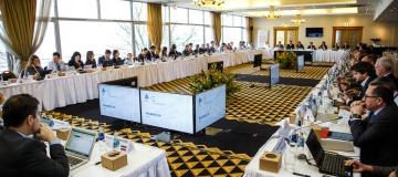 The image shows multiple participants sitting at a U-shaped table group