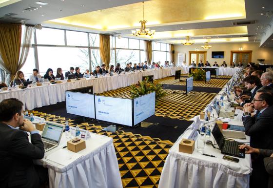 The image shows multiple participants sitting at a U-shaped table group